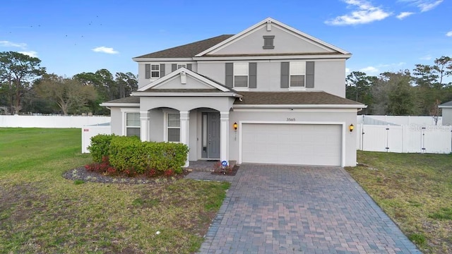 traditional-style home featuring fence, decorative driveway, a gate, stucco siding, and a front lawn