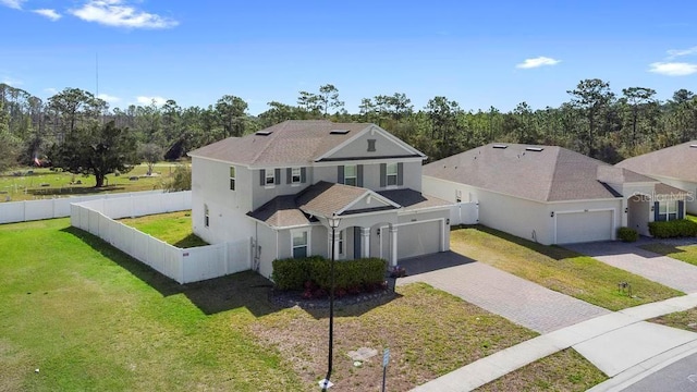 view of front of house featuring decorative driveway, a fenced backyard, a front lawn, and stucco siding