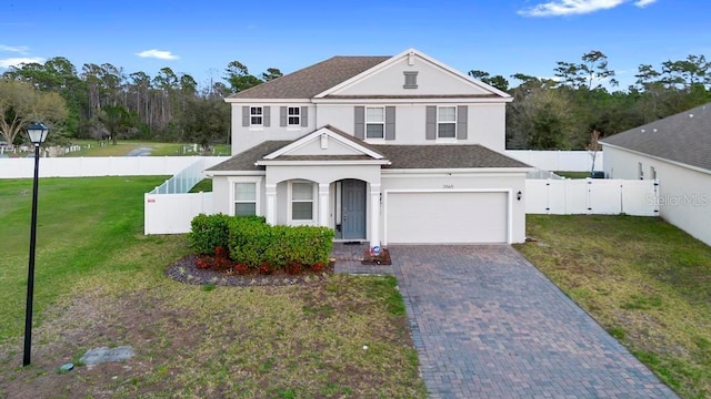 traditional-style home featuring a fenced backyard, a garage, decorative driveway, stucco siding, and a front yard