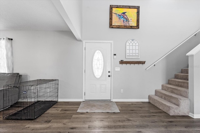 foyer with stairs, baseboards, and wood finished floors