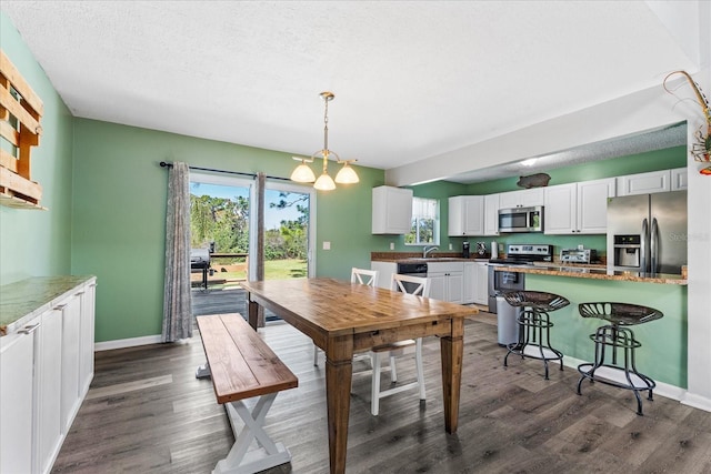 dining room with dark wood-style floors, a textured ceiling, and baseboards