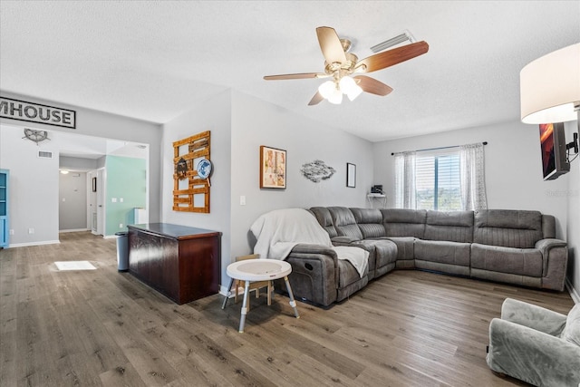 living area featuring a textured ceiling, ceiling fan, wood finished floors, and visible vents