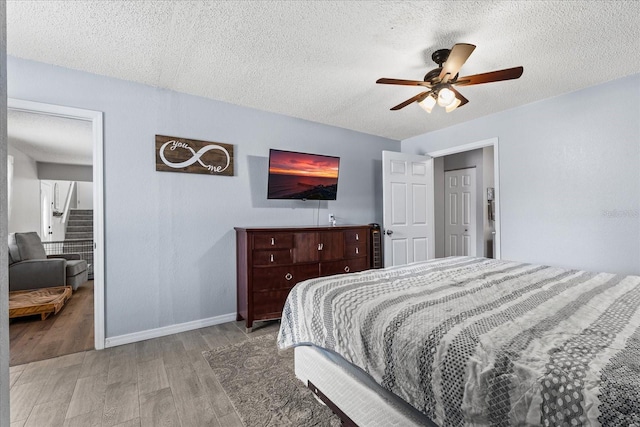 bedroom featuring a textured ceiling, ceiling fan, wood finished floors, and baseboards