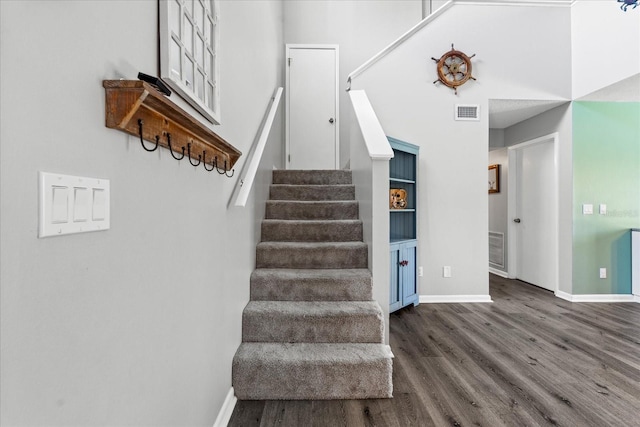 stairs featuring wood finished floors, visible vents, and baseboards