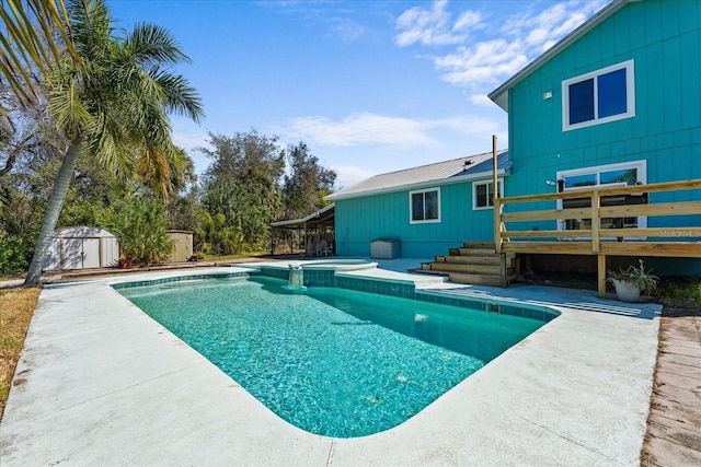 view of swimming pool featuring a pool with connected hot tub, a patio area, a shed, an outdoor structure, and a wooden deck