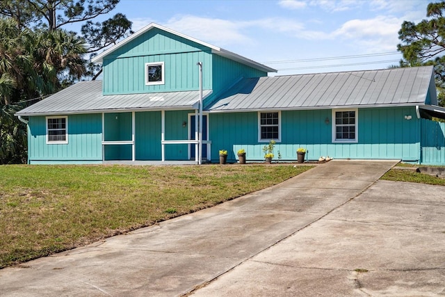 view of front of property with driveway, metal roof, a front lawn, and a porch