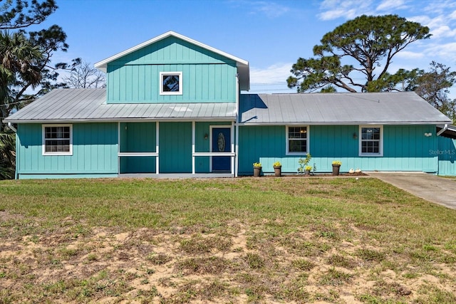 view of front of house featuring a porch, metal roof, and a front lawn