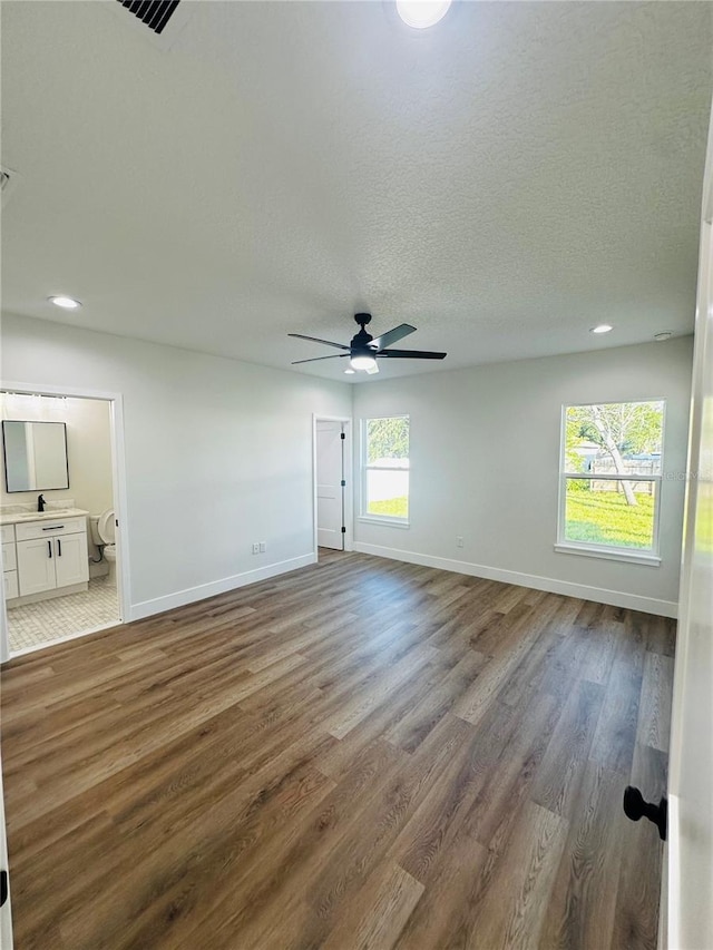 unfurnished room with a textured ceiling, baseboards, and wood finished floors