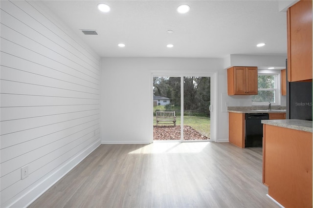 kitchen featuring wood walls, light countertops, brown cabinets, dishwasher, and light wood finished floors