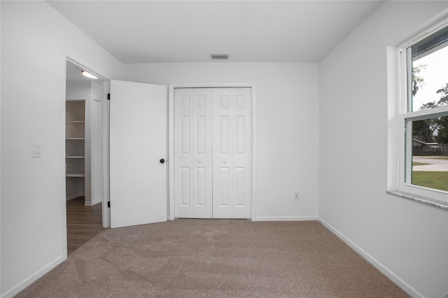 unfurnished bedroom featuring baseboards, carpet, visible vents, and a closet