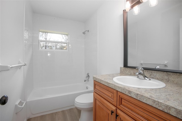 bathroom featuring toilet, vanity, wood finished floors, and shower / bathing tub combination