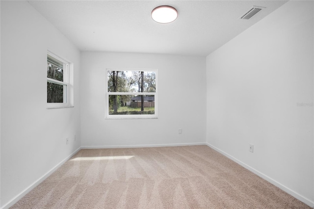 unfurnished room featuring carpet, visible vents, and baseboards