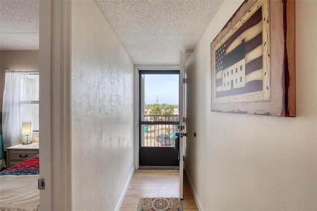 doorway featuring a textured ceiling, baseboards, and wood finished floors