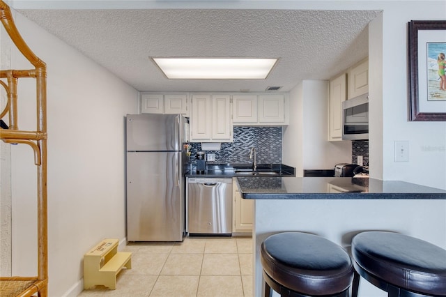 kitchen featuring dark countertops, appliances with stainless steel finishes, backsplash, and a sink