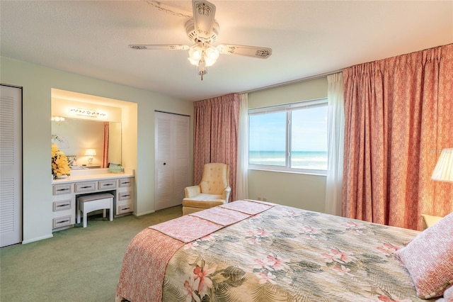 bedroom featuring ceiling fan, multiple closets, and light colored carpet