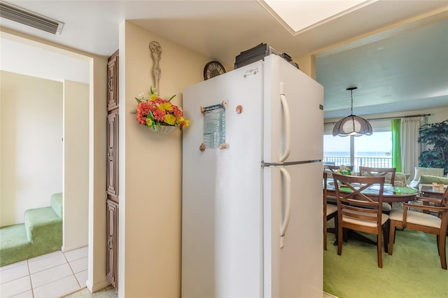 kitchen featuring visible vents, light tile patterned flooring, freestanding refrigerator, and pendant lighting