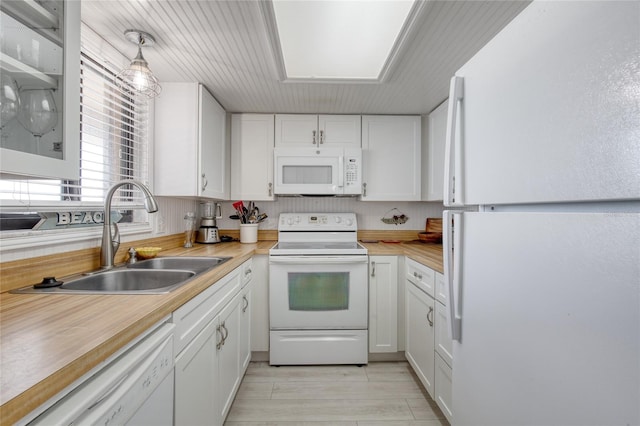 kitchen with light countertops, white appliances, a sink, and white cabinets