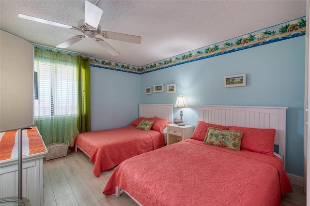 bedroom with light wood-style flooring, ceiling fan, and a textured ceiling