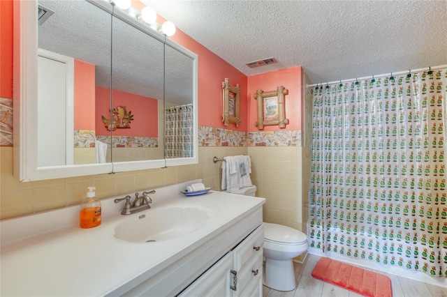 full bath featuring tile walls, toilet, a textured ceiling, vanity, and a shower with curtain