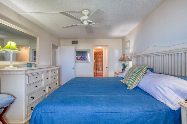 bedroom featuring a textured ceiling, ensuite bathroom, visible vents, and a ceiling fan