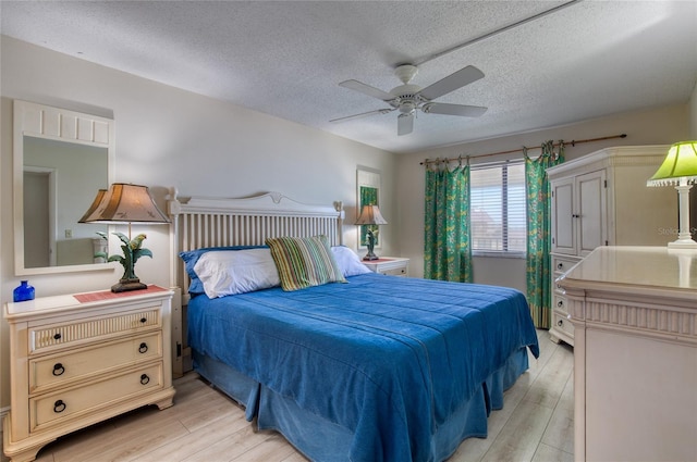 bedroom with light wood-style floors, ceiling fan, and a textured ceiling