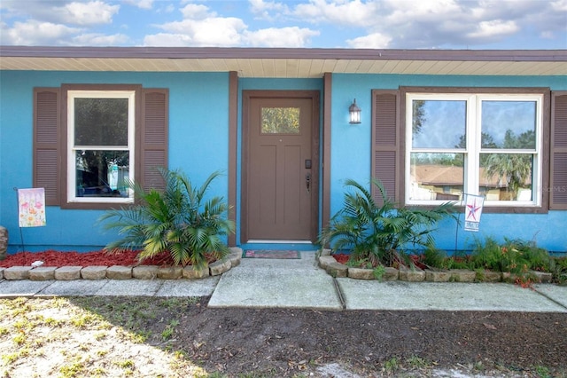 doorway to property featuring stucco siding