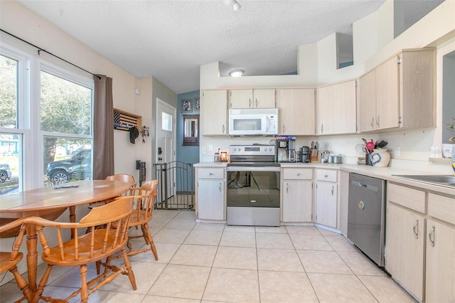 kitchen featuring stainless steel appliances, light countertops, light tile patterned flooring, and a textured ceiling