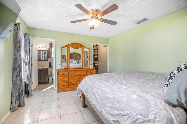 bedroom with light tile patterned floors, a textured ceiling, visible vents, and a ceiling fan