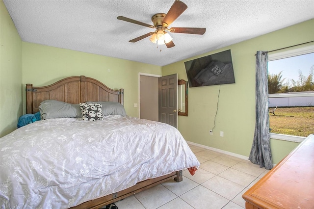 bedroom featuring a ceiling fan, a textured ceiling, baseboards, and light tile patterned floors