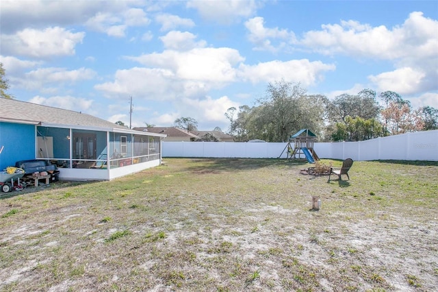 view of yard featuring a playground, a fenced backyard, and a sunroom