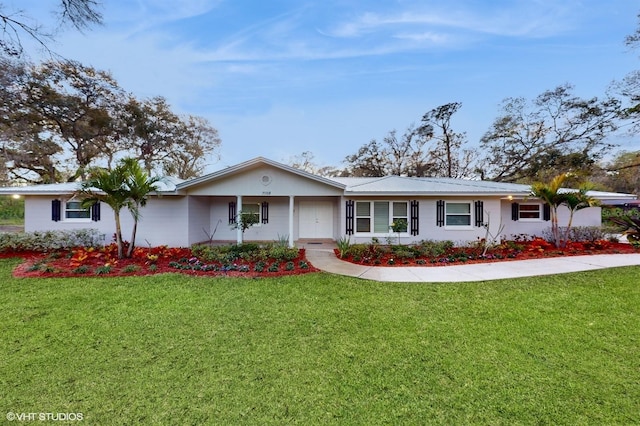 ranch-style home with a front yard and metal roof