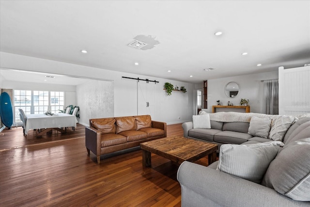 living room with recessed lighting, visible vents, a barn door, wood finished floors, and baseboards