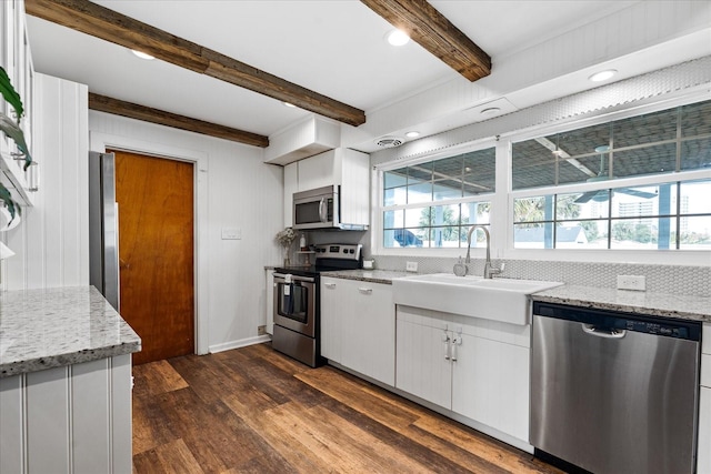 kitchen with a sink, white cabinets, appliances with stainless steel finishes, beam ceiling, and dark wood finished floors