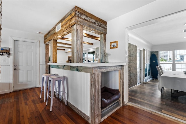 kitchen with dark wood-type flooring, baseboards, and a kitchen bar