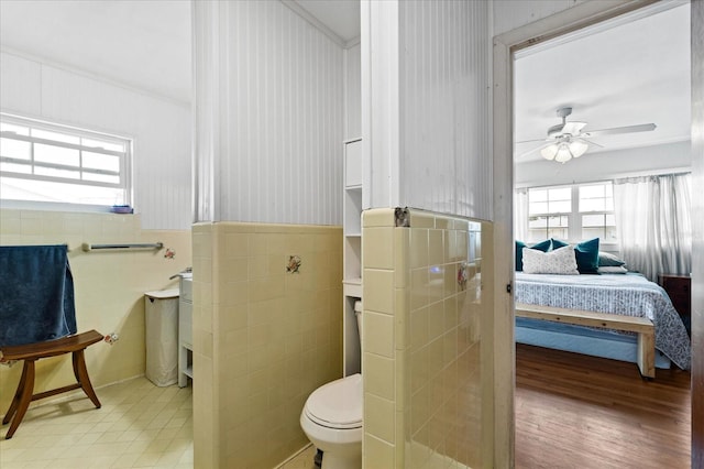 bathroom with plenty of natural light, toilet, and tile walls