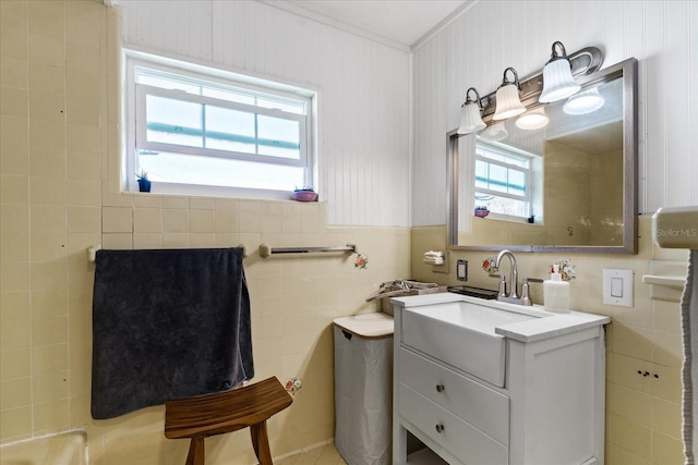 bathroom featuring ornamental molding, wainscoting, tile walls, and vanity