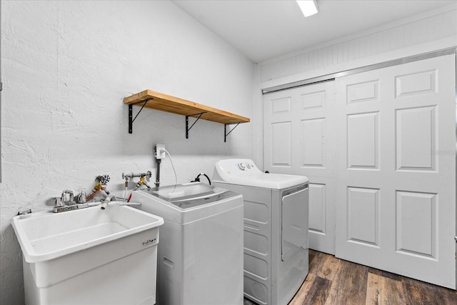 laundry room featuring a textured wall, laundry area, dark wood-style flooring, a sink, and independent washer and dryer