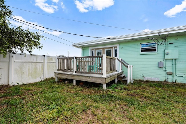 rear view of house with a wooden deck, fence, and a yard