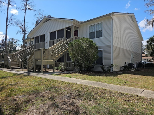 view of front of home with a front yard, a sunroom, central AC, and stairway