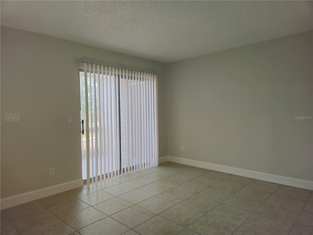 unfurnished room featuring a textured ceiling, tile patterned flooring, and baseboards