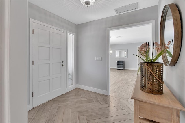 foyer with a textured ceiling, visible vents, and baseboards