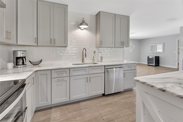 kitchen with stainless steel appliances, light wood-type flooring, gray cabinets, and a sink