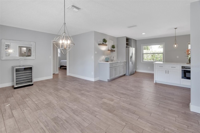 kitchen featuring visible vents, stainless steel fridge with ice dispenser, wine cooler, open shelves, and black oven