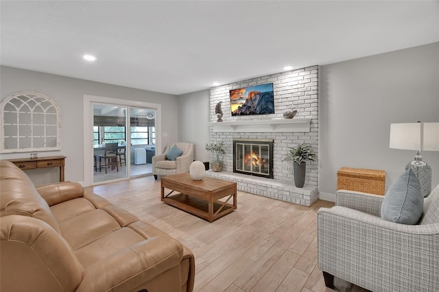 living area featuring light wood-type flooring, a brick fireplace, baseboards, and recessed lighting