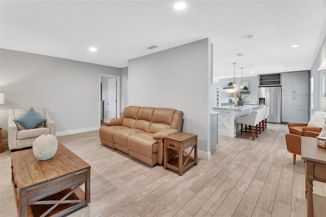 living room with light wood-type flooring, visible vents, and baseboards