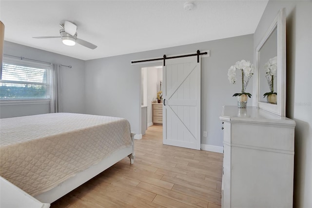 bedroom with a ceiling fan, light wood-style flooring, baseboards, and a barn door