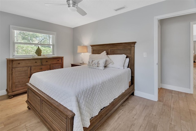 bedroom with light wood-style floors, visible vents, baseboards, and a ceiling fan