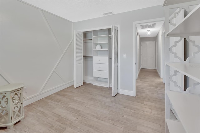 bedroom with light wood-style floors, a closet, and visible vents