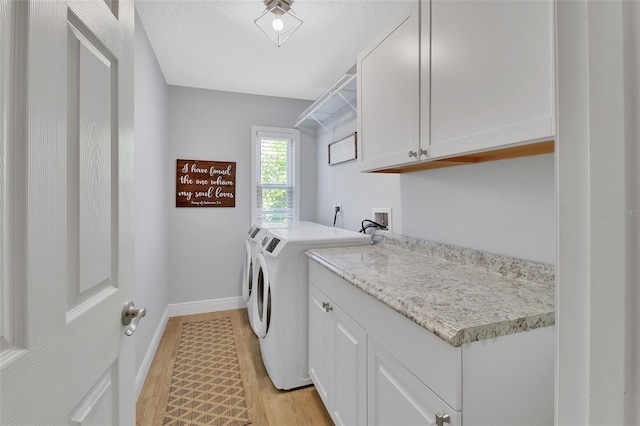 laundry area with light wood-type flooring, cabinet space, baseboards, and washing machine and clothes dryer