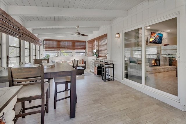 sunroom / solarium featuring lofted ceiling with beams, a brick fireplace, and a ceiling fan